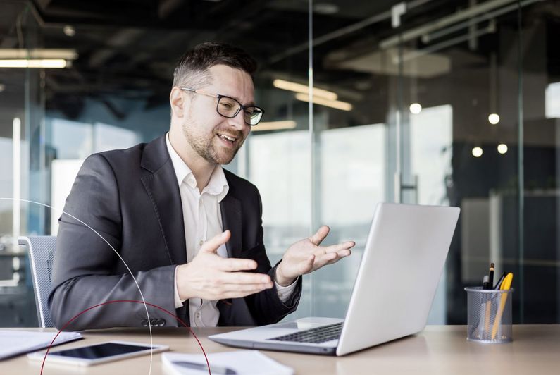 Ein Mann sitzt an seinem Arbeitsplatz und schaut auf seinen Laptop.