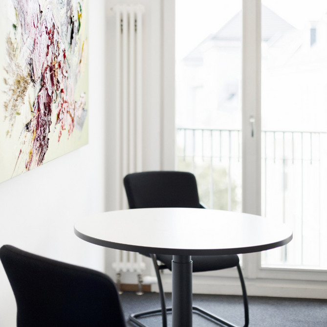 Ein weißer runder Tisch mit zwei schwarzen Stühlen