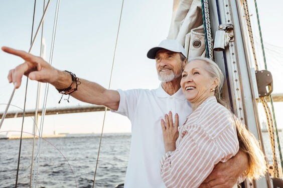 Ein älteres Paar auf einem Segelboot. Der Mann deutet in die Ferne.