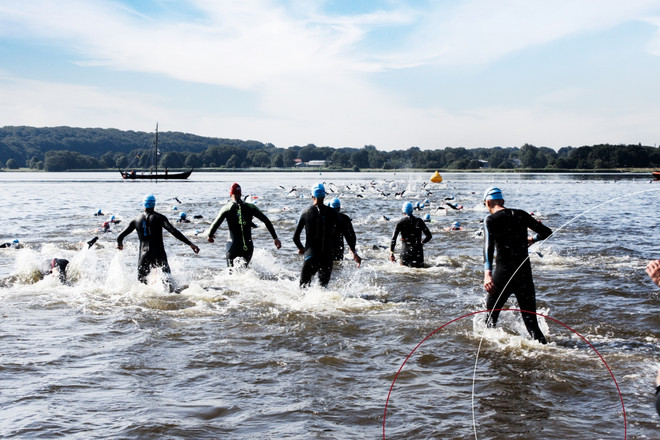 Sechs ttpler laufen mit neoprenanzügen ins Wasser