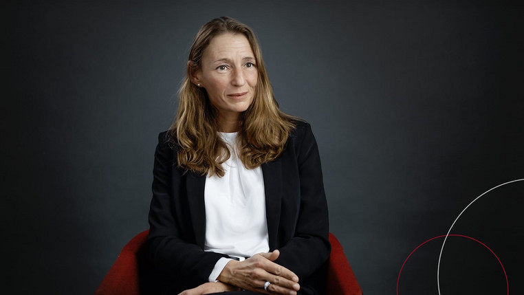 Beate Theede sitzt vor schwarzem Hintergrund