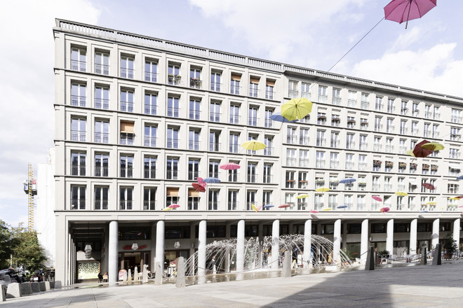 Außenansicht auf ein weißes Gebäude mit bunten Regenschirmen