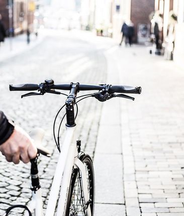 Ein Mann schiebt ein weißes Fahrrad
