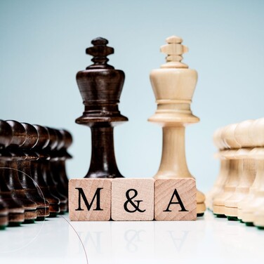 Aufgereihte Schachfiguren nach Farben sortiert. Davor Würfel mit M & A