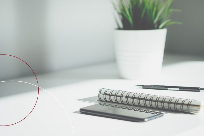 Smartphone, Notizbuch und Stift liegen auf einem Tisch