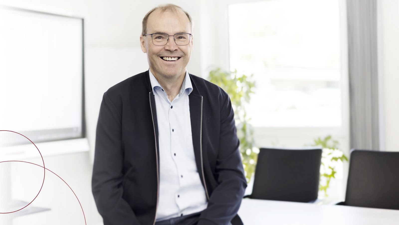 Der Kollege Frank Hansen lehnt an einem Tisch und lächelt in die Kamera.