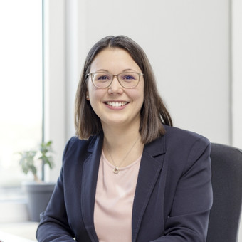 Headergrafik: Dr. Katharina Theis am Schreibtisch sitzend