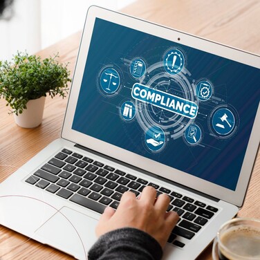 Aufgeklapptes Notebook zeigt Compliance-Grafik im quadratischen Zuschnitt