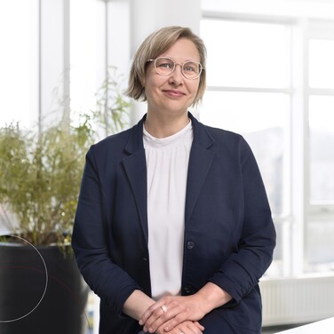 Kollegin Inga Bauch steht in ihrem Büro und lächelt in die Kamera.