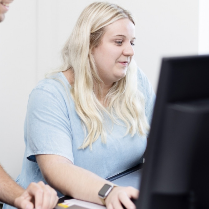 Zwei ttp Mitarbeiter stehen vor einem PC