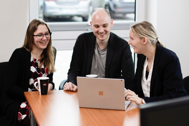 Drei Kollegen von ttp sitzen vor einem Laptop
