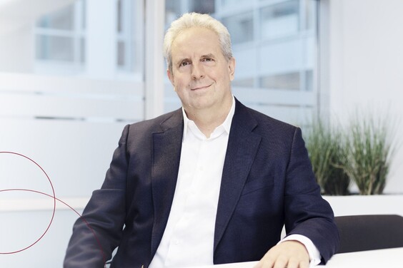 Robert Binder sitzt lächelnd am Schreibtisch
